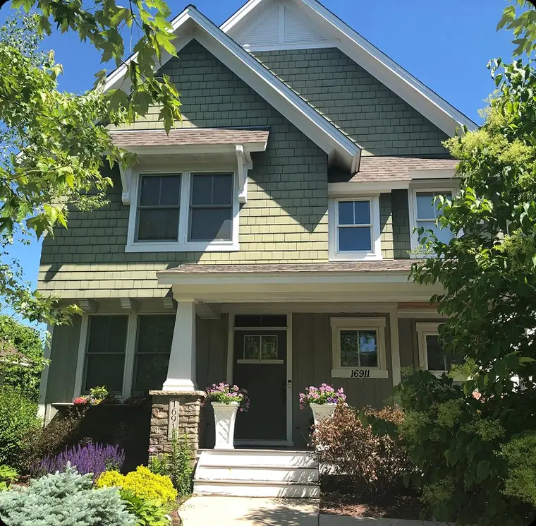 Green craftsman-style house with a covered porch and flower pots